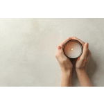 Hands holding a lit candle in a round container