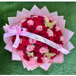 Bouquet of red and pink roses wrapped in pink paper with a ribbon