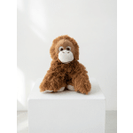 Brown plush monkey sitting on a white pedestal