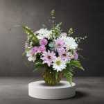 Pink and white daisy bouquet in a round glass vase