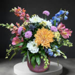 Colorful mixed flower arrangement in a round purple vase