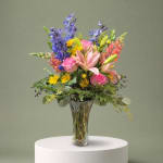 Mixed bouquet of pink, purple, and yellow flowers in a clear glass vase