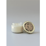 Two white candles in glass jars, one with a labeled metal lid