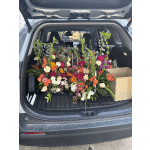 Car trunk filled with colorful mixed flower arrangements and boxes