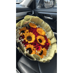 Bouquet of red roses and yellow sunflowers wrapped in pale paper