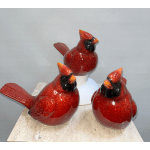 Three glossy red cardinal figurines on a tabletop