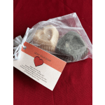 Two wrapped bars of goat milk soap with a gift tag on red fabric