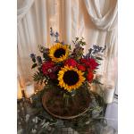 Sunflowers, red roses, and purple flowers in a glass vase