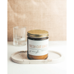 Scented candle in a glass jar with a gold lid on a tray