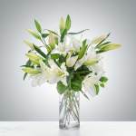 White lilies and unopened buds in a clear glass vase