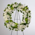 Standing wreath of white roses and green blooms on a black metal easel