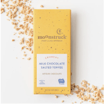 Yellow milk chocolate salted toffee bar with toffee pieces scattered on a white surface