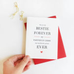 Hand holding a greeting card with red envelope and gold clips