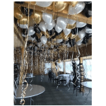Ceiling filled with gold, white, and black balloons with hanging streamers