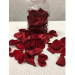 Clear bag of red rose petals spilled onto a white surface