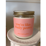Pink-labeled jar candle with gold lid on a white ceramic pedestal stand