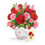 Bouquet of red and pink roses in a glass vase with a greeting card