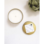 White candle in a gold tin with a labeled lid