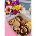 Box of assorted donuts with a colorful flower bouquet