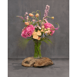 Tall bouquet of pink hydrangeas, peach roses, and lavender flowers in a glass vase