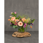 Mixed bouquet of peach, pink, purple, and orange flowers in a glass vase