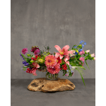 Colorful mixed bouquet in a clear glass vase on a wooden base