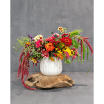 Colorful mixed flower arrangement in a white vase on a wooden base