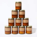 Stack of amber glass candles with gold lids and paper labels