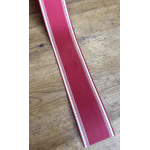 Long red ribbon with white trim on a wooden surface