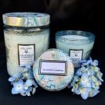 Three decorative candles with blue hydrangea blooms on a black background