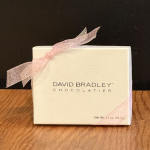 White chocolate box with a pink ribbon on a wooden surface