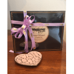 Box of chocolates tied with a pink ribbon, with a heart-shaped dish in front