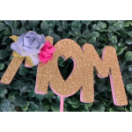 Glittery gold "MOM" sign with small pink and lavender flowers