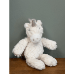 White plush unicorn toy with a silver horn sitting on a wooden surface