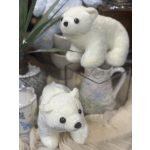 Two white plush polar bears on a shelf with mugs and decor