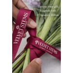 Hands tying a burgundy florist ribbon around a bouquet of green stems