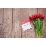 Red tulip bouquet beside a thank-you card on a wooden surface