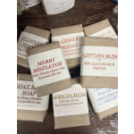 Assorted wrapped soap bars with scented labels on a wooden surface