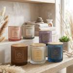 Assorted scented candles in ribbed glass jars on a wooden shelf