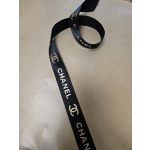 Black Chanel ribbon with gold logos on a beige surface