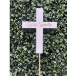 White cross sign with "With Sympathy" text against a leafy backdrop