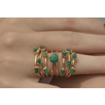 Gold rings with green stones stacked on a finger
