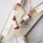 Four Lollia perfume bottles with red cords and small keys on a light surface