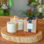 Three candles and a gift box on a wooden slab
