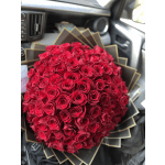 Large round bouquet of tightly packed red roses wrapped in layered black and gold paper.