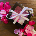 Black gift box tied with a white ribbon, surrounded by pink rose petals