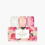 Trio of faceted glass candles in white, peach, and pink on a rose-printed gift box