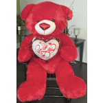 Large red teddy bear holding a heart pillow that says I Love You