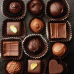 Assorted chocolate truffles in paper cups on a dark surface