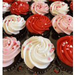 Assorted cupcakes with red, pink, and white frosting swirls and heart sprinkles